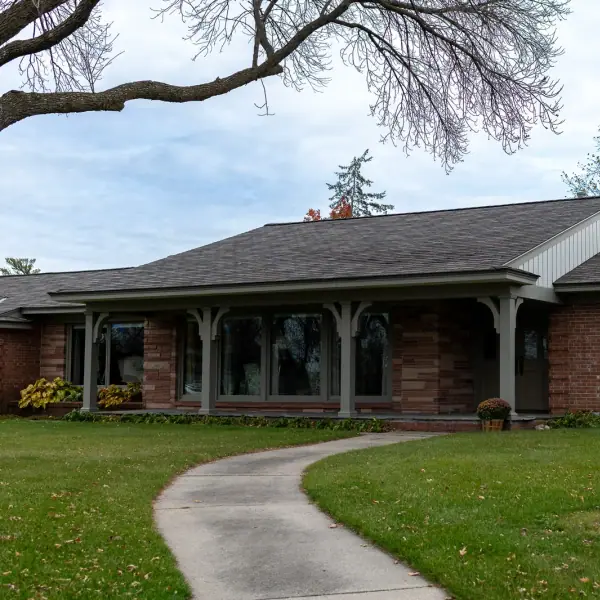 Front of a long brick ranch home with a new shingle roof and a covered entry porch.