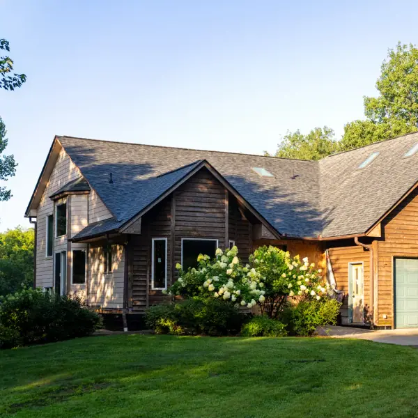 Cedar-sided two-story home with a new charcoal architectural shingle roof at golden hour.